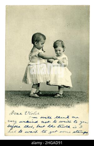 Carte postale de voeux édouardienne représentant deux enfants / tout-petits cute tenant les mains, le bébé sur la gauche est probablement un garçon portant une robe comme c'était normal à ce moment, publié en 1904 du Royaume-Uni Banque D'Images