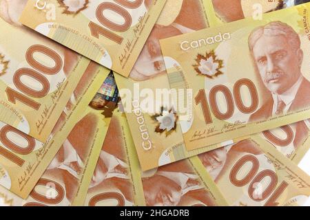 A directement au-dessus de l'image de billets de cent dollars canadiens nets de 100 sur fond blanc.Les billets sont empilés au hasard l'un sur l'autre. Banque D'Images