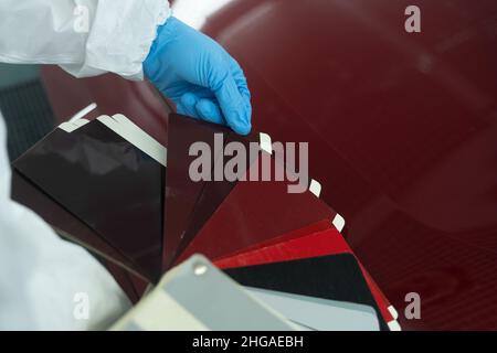 Le préposé à l'atelier de carrosserie choisit la couleur de peinture appropriée avant de peindre le véhicule Banque D'Images