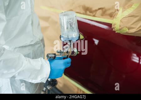 Gros plan de la main d'un peintre automobile avec un pistolet pulvérisateur dans sa main Banque D'Images