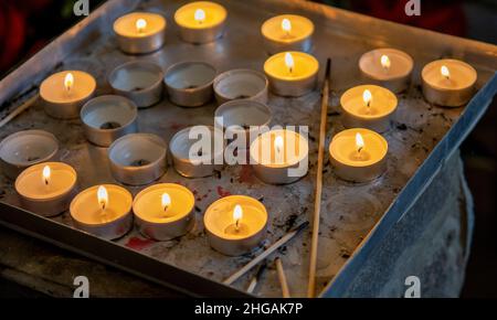 Bougies de prière brûlantes à l'intérieur d'une église catholique.Lumières à thé allumées.Mise au point sélective. Banque D'Images