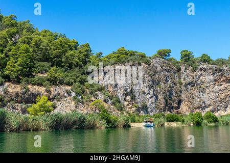 Bateau de plaisance touristique sur la rivière Dalyan, à côté des rochers, qui contiennent les tombes lyciennes, dans la province de Mugla, Turquie Banque D'Images