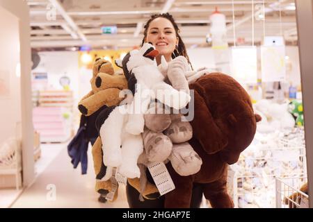 shopaholic.La fille dans le magasin a marqué des jouets, un shopaholic.La fille a acheté un tas de choses inutiles et est heureuse. Banque D'Images