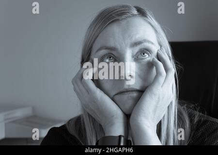 Femme ennuyée assise dans le bureau et regardant dans le plafond Banque D'Images