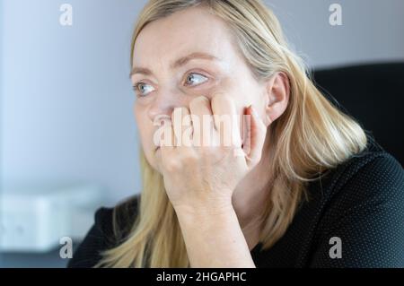 Femme ennuyée assise dans le bureau et regardant dans le plafond Banque D'Images