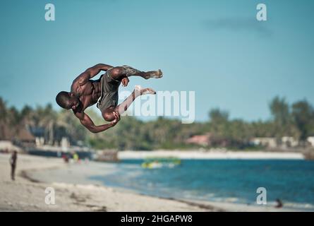 Action acrobatioc saut de jeune africain.Rotation aérienne de Am man sur la plage à Watamu Kenya, Afrique jeune homme saut arrière-flip noir blanc Banque D'Images