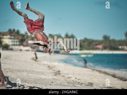 Action acrobatioc saut de jeune africain.Rotation aérienne de Am man sur la plage à Watamu Kenya, Afrique jeune homme saut arrière-flip noir blanc Banque D'Images