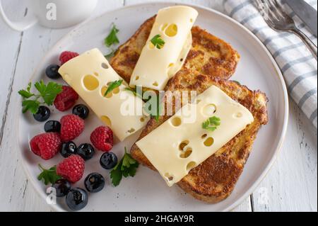 Sandwich de petit déjeuner au fromage préparé avec du pain grillé et servi avec des baies fraîches sur une assiette blanche Banque D'Images