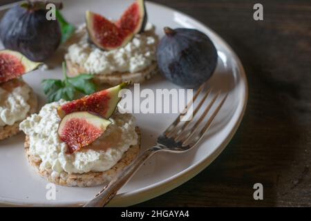 Assiette avec petit déjeuner sain. Fait de craquelins de riz brun, fromage cottage et figues. Servi isolé sur une table en bois. Banque D'Images
