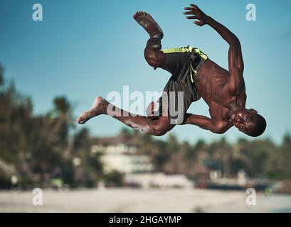 Action acrobatioc saut de jeune africain.Rotation aérienne de Am man sur la plage à Watamu Kenya, Afrique jeune homme saut arrière-flip noir blanc Banque D'Images