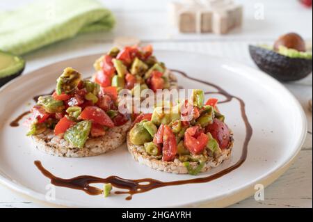 Salade d'avocats aux tomates et sauce balsamique servie sur des craquelins de riz brun Banque D'Images
