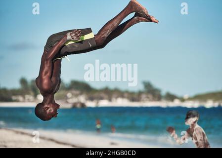 Action acrobatioc saut de jeune africain.Rotation aérienne de Am man sur la plage à Watamu Kenya, Afrique jeune homme saut arrière-flip noir blanc Banque D'Images