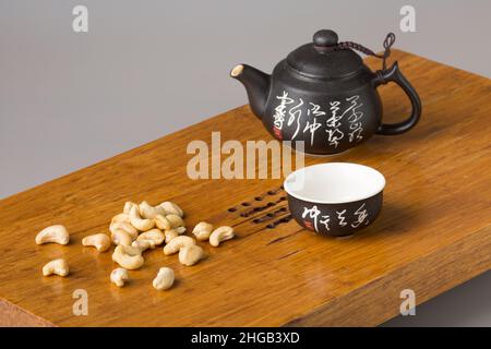 Tasse à thé et théière asiatiques traditionnelles.Service et noix de cajou sur une table en bois pour les cérémonies du thé.Le concept de minimalisme. Banque D'Images