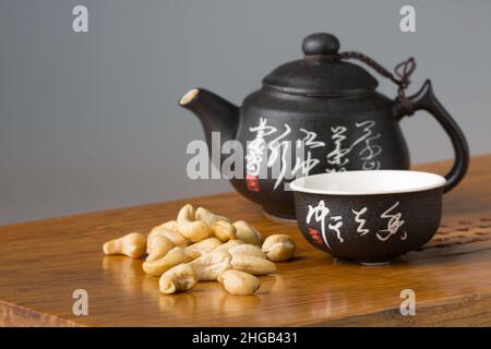 Tasse à thé et théière asiatiques traditionnelles.Service et noix de cajou sur une table en bois pour les cérémonies du thé.Le concept de minimalisme. Banque D'Images