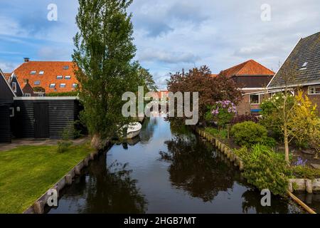 Canal d'eau entre les maisons à Hindeloopen en Hollande.Il y a un bateau sur l'eau et son reflet dans l'eau. Banque D'Images