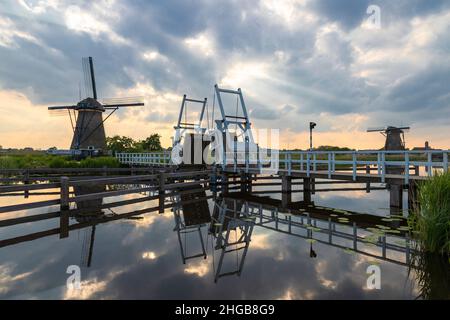 Beau moulin à vent et pont-levis sur un canal à Kinderdijk en Hollande.Le moulin et les nuages se reflètent dans l'eau.Il y a des nuages spectaculaires dans le Th Banque D'Images