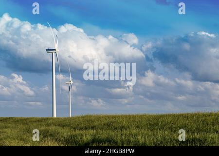 Moulins à vent sur prairie verte.L'arrière-plan est un beau ciel bleu avec des nuages blancs par temps ensoleillé.Il y a de l'herbe verte autour. Banque D'Images