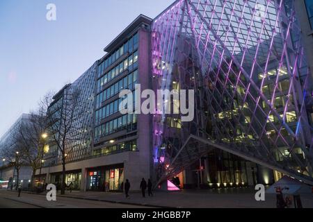 L'atrium du 55 Baker Street, Londres, présente des lumières violettes entre les panneaux de verre et semble impressionnant au crépuscule lorsque les piétons et les bus passent Banque D'Images