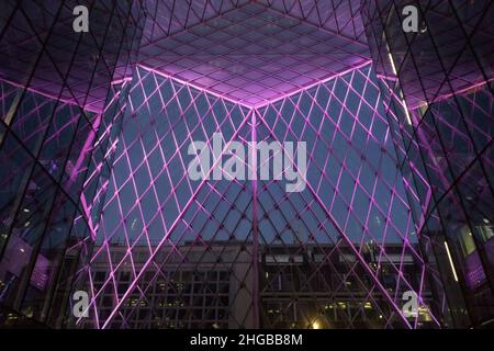 L'atrium du 55 Baker Street, Londres, présente des lumières violettes entre les panneaux de verre et semble impressionnant au crépuscule lorsque les piétons et les bus passent Banque D'Images