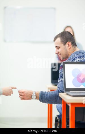 Les élèves passent secrètement des feuilles de papier pendant l'examen dans une salle de classe moderne Banque D'Images