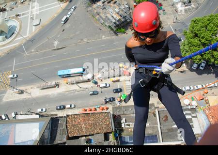 Une femme portant un costume de héros avec un casque de protection marchant dans un grand bâtiment de Rappel.Salvador Bahia Brésil. Banque D'Images