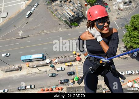 Une femme portant un costume de héros avec un casque de protection marchant dans un grand bâtiment de Rappel.Salvador Bahia Brésil. Banque D'Images