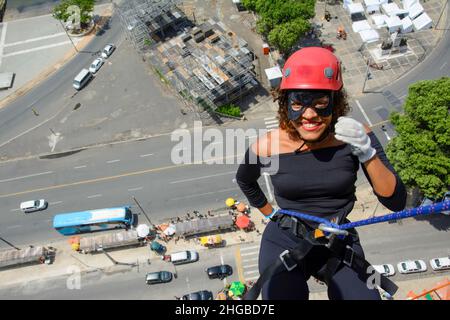 Une femme portant un costume de héros avec un casque de protection marchant dans un grand bâtiment de Rappel.Salvador Bahia Brésil. Banque D'Images