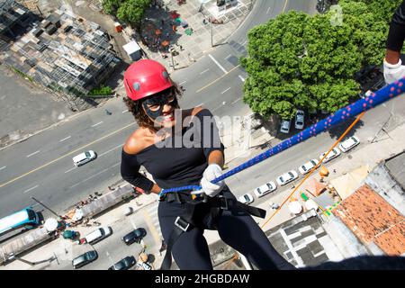 Une femme portant un costume de héros avec un casque de protection marchant dans un grand bâtiment de Rappel.Salvador Bahia Brésil. Banque D'Images