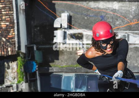 Une femme portant un costume de héros avec un casque de protection marchant dans un grand bâtiment de Rappel.Salvador Bahia Brésil. Banque D'Images