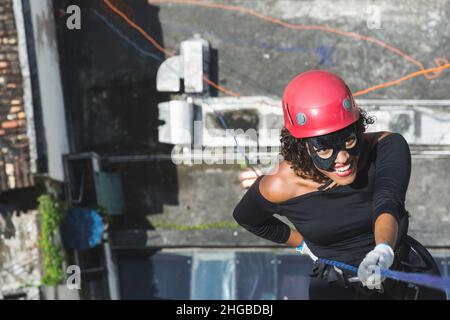 Une femme portant un costume de héros avec un casque de protection marchant dans un grand bâtiment de Rappel.Salvador Bahia Brésil. Banque D'Images