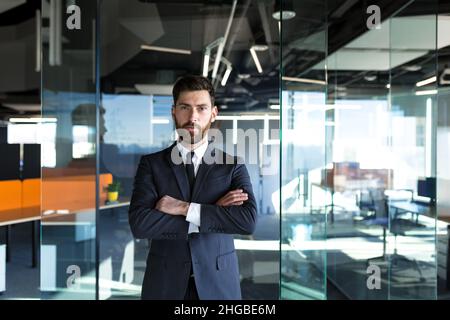 Homme d'affaires prospère regardant la caméra avec les bras croisés, propriétaire sérieux d'affaires dans le bureau moderne Banque D'Images