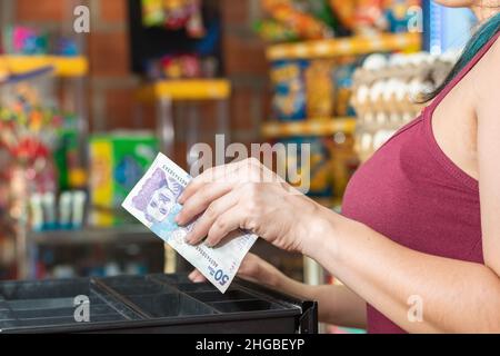 main de la femme latina ouvrant la caisse. retirer l'argent après avoir fait une vente, fille travaillant dans le magasin de quartier colombien. cinquante mille peso Banque D'Images