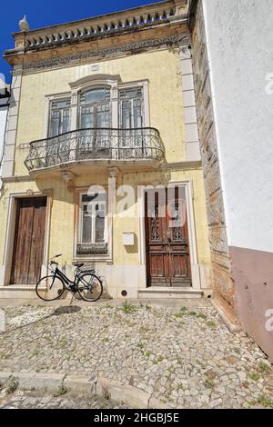 Façade en carreaux jaunes-maison néoclassique-portes en bois écaillées-balustrade en métal-vélo noir.Tavira-Portugal-066 Banque D'Images