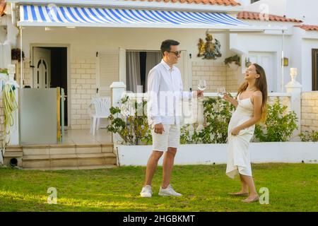 Belle fille dans une robe blanche sur une date avec un homme en blanc.Couple célébrant l'achat d'une maison au bord de l'océan.Un couple magnifique boit du vin près de la h Banque D'Images