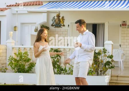 Belle fille dans une robe blanche sur une date avec un homme en blanc.Couple célébrant l'achat d'une maison au bord de l'océan.Un couple magnifique boit du vin près de la h Banque D'Images