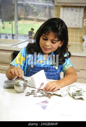 Austin Texas États-Unis, 1998 : huit ans, une jeune fille panaméenne-américaine prépare le dépôt pour le compte d'épargne à partir de dollars et de pièces qu'elle a économisé.. MR ©Bob Da Banque D'Images