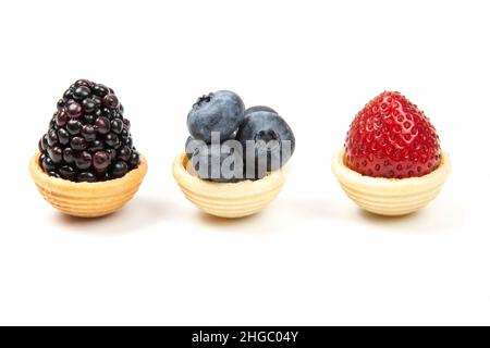 bleuets, fraises et mûres dans des corbeilles à gaufres sur fond blanc Banque D'Images