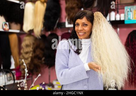 Femme choisissant la perruque naturelle à la boutique spécialisée Banque D'Images