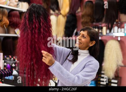 Femme choisissant la perruque naturelle à la boutique spécialisée Banque D'Images