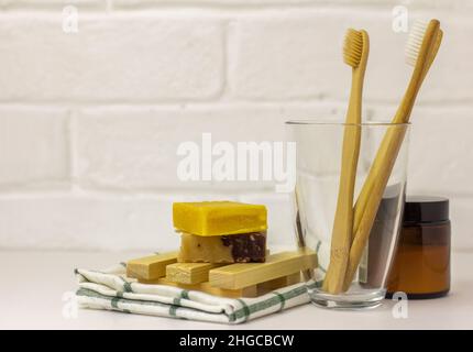 Brosses à dents en bambou écologiques dans un bécher en verre, poudre de dent naturelle et savon biologique fait main, espace de copie Banque D'Images