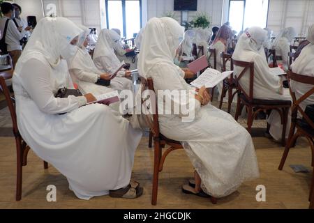 Jakarta, Indonésie - décembre 2020 : Un groupe de femmes musulmanes porte un masque facial et lit des livres de prière dans une salle Banque D'Images