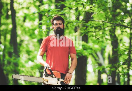 Beau jeune homme avec hache près de la forêt.Concept de bûcherons.Thème de l'agriculture et de la foresterie.Déforestation.Le bois de chauffage comme source d'énergie renouvelable. Banque D'Images