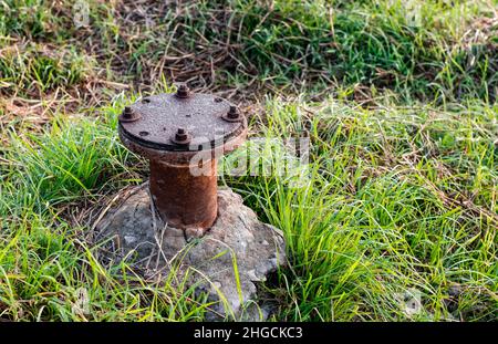 Ancien tuyau de filtre rustique abandonné d'une pompe à eau sur un champ agricole de près Banque D'Images