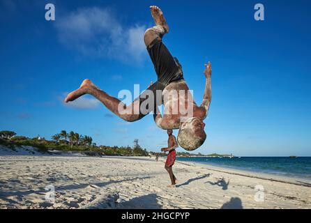 Garçon exécutant action saut acrobatique de jeunes hommes africains rotation aérienne d'un homme sur la plage à Watamu, Kenya, Afrique saut jeune homme Banque D'Images