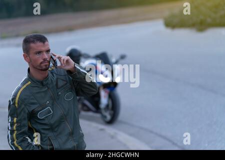 Jeune homme avec panne de moto sur la route parlant au téléphone Banque D'Images