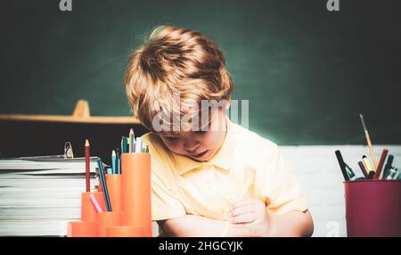 Concept scolaire.Espace de copie de tableau noir - concept d'école.Espace de copie du tableau noir.Joyeux mignon enfant industriel est assis à un bureau à l'intérieur Banque D'Images