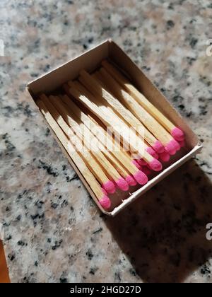 Boîte en carton avec allumettes roses sur une table en granit gris Banque D'Images