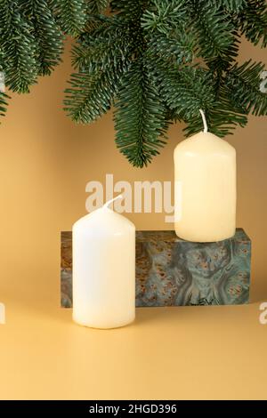 Un podium en bois stabilisé et un sapin de Noël avec des bougies sur fond jaune.Mise en page pour la démonstration de produits cosmétiques.Copier l'espace Banque D'Images