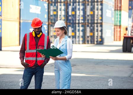 Femme d'affaires et ingénieur parlant et vérifiant le chargement de la boîte de conteneurs à partir du fret cargo navire pour l'importation exportation. Expédition dans les quais. Banque D'Images