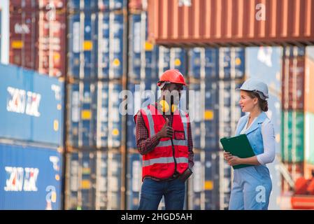 Femme d'affaires et ingénieur parlant et vérifiant le chargement de la boîte de conteneurs à partir du fret cargo navire pour l'importation exportation. Expédition dans les quais. Banque D'Images